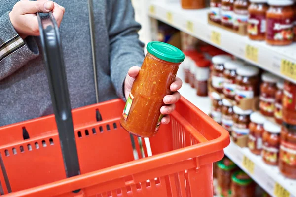 Glazen pot van ingeblikte groenten in handen koper — Stockfoto