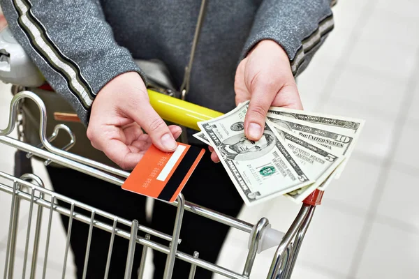 Bank card and dollar bills in hand at store — Stock Photo, Image