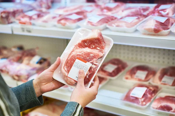 Las manos del comprador con carne de cerdo en el supermercado — Foto de Stock