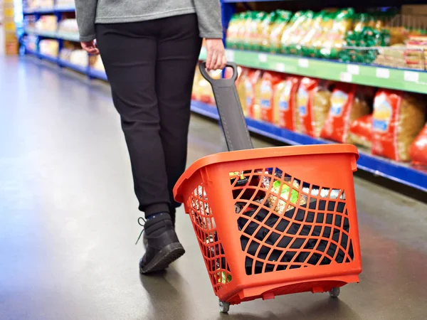 Žena s nákupní vozík v supermarketu s potravinami — Stock fotografie