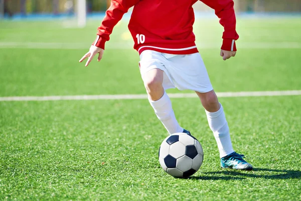 Foot of a child football player and ball on the football field