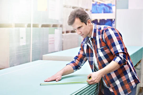 Muž měří sádrokartonové desky v obchodě — Stock fotografie