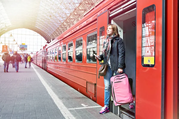 Женщина-туристка с чемоданом выходит из поезда — стоковое фото