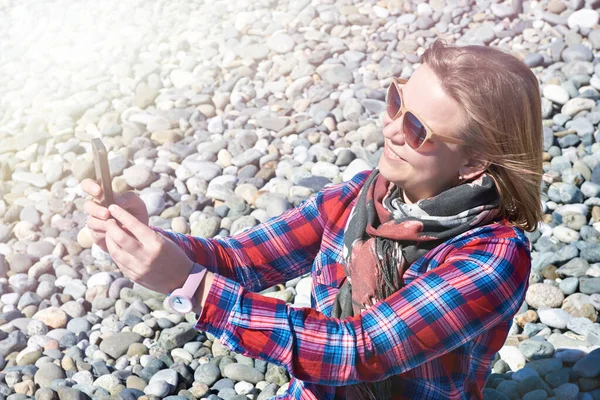 Mooi meisje met telefoon op rotsachtig strand — Stockfoto
