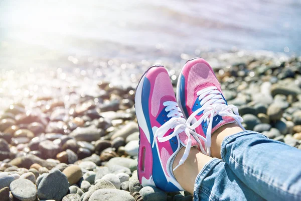 Sneakers girl on background of sea and rocky beach — Stock Photo, Image