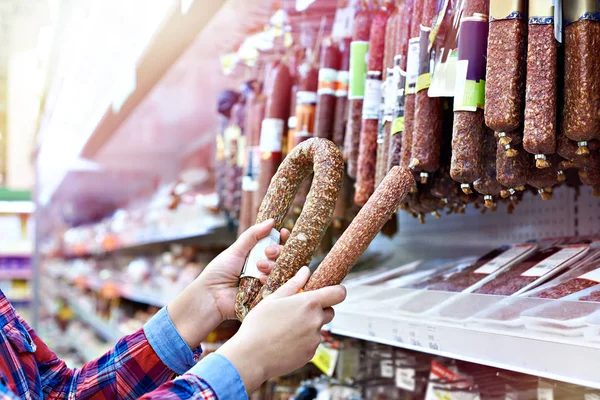 Vrouw met gerookte worst in de winkel — Stockfoto