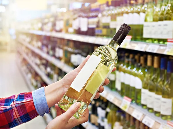Woman with bottle of wine in store — Stock Photo, Image