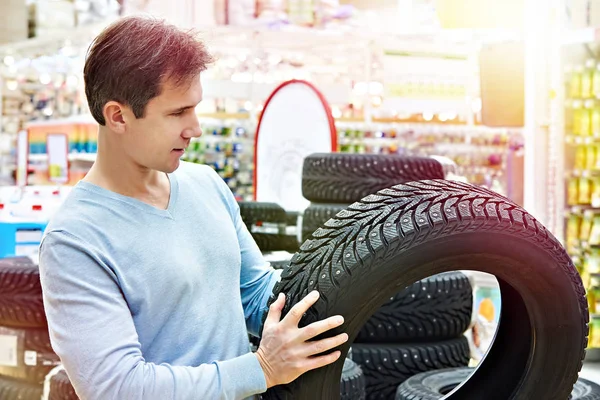 El hombre elige neumáticos de invierno tachonado para el coche —  Fotos de Stock