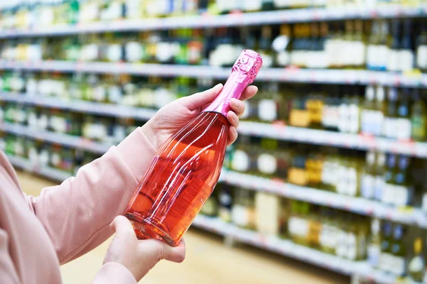 Bottle of rose wine in hands at store — Stock Photo, Image