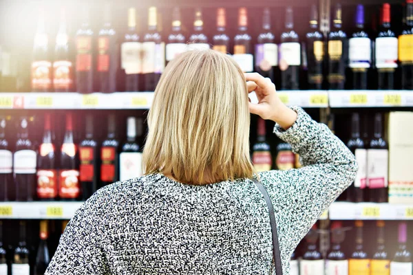 Girl chooses wine in a supermarket