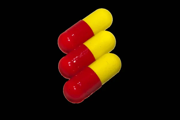 Pillole mediche isolate su uno sfondo nero — Foto Stock