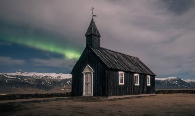 Kuzey ışıkları İzlanda 'daki siyah kilisesinin üzerinde aurora borealis.