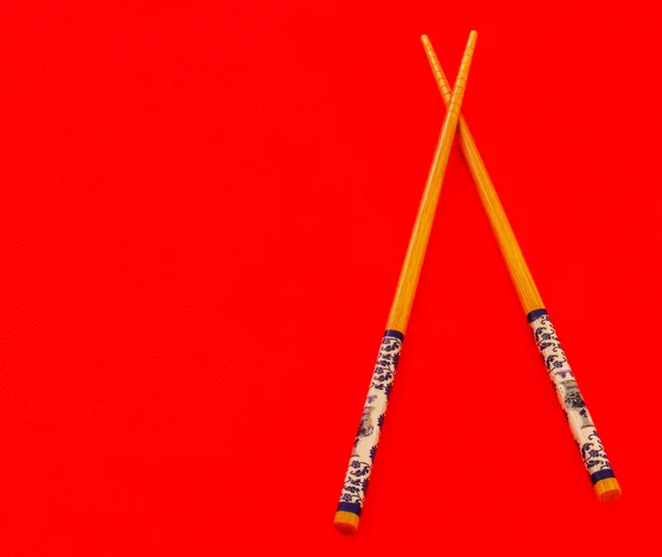 Bir çift kırmızı bir arka plan üzerinde Asya yemek çubukları.