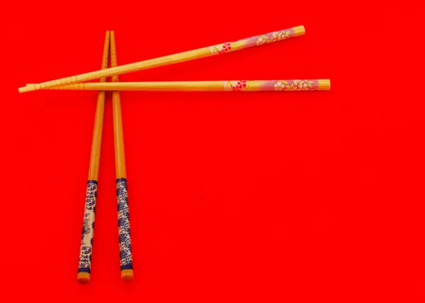 Kırmızı bir arka plan üzerinde Asya yemek çubukları iki çift.