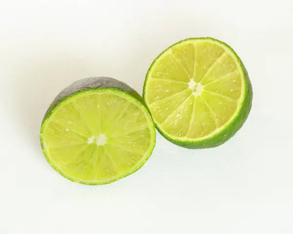 Beyaz arka plan üzerinde izole yarım dilimlenmiş yeşil kireç yakın çekim.