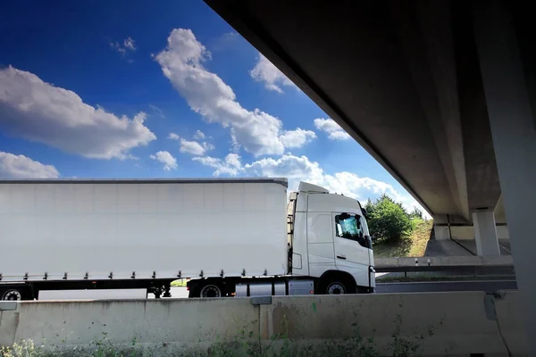 Vrachtwagen vervoer op de weg onder brug — Stockfoto