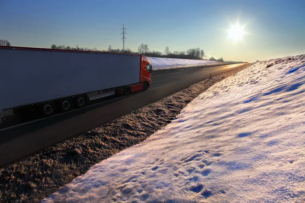 Vrachtwagen vervoer op de weg bij zonsondergang in de winter — Stockfoto