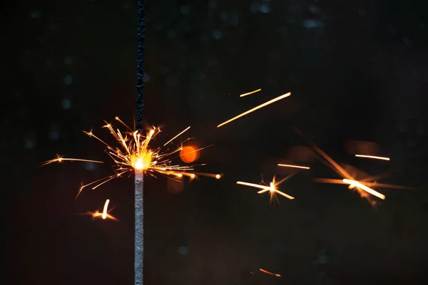 sparkler near a dark window covered with raindrops