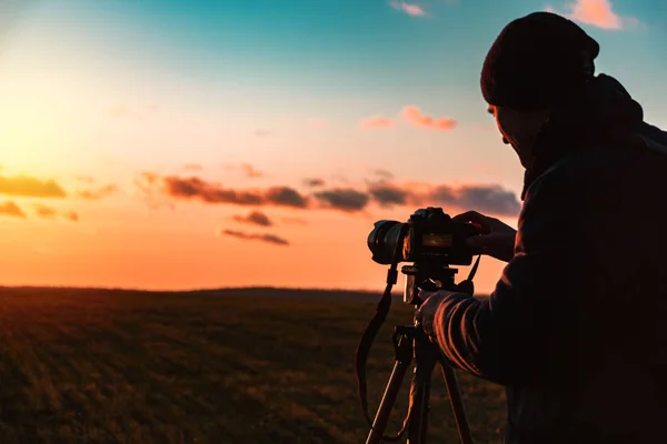 三脚とカメラを持つ写真家は広いオープンエリアで日没時に風景を撮影します — ストック写真