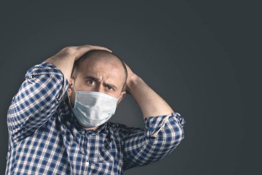 Siyah arka planda mavi koruyucu tıbbi maskeli genç adam.