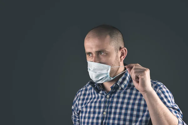 young man in blue protective medical mask on a dark background