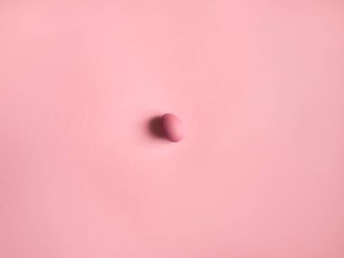 Ortada pembe yumurta üstten görünüm pembe bir arka plan üzerinde