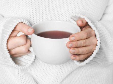 Beyaz kupa elinde tutan sıcak beyaz kazaklı kadın