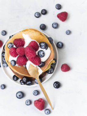 lezzetli taze yaban mersini ve beyaz masa, üstten görünüm üzerinde tahta kaşıkla plaka üzerinde ahududu ile krep yığını