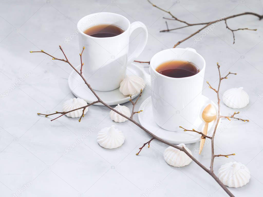 coffee cups and meringue cookies with spoon on white background with copy space
