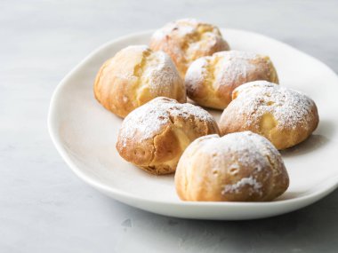 Beyaz tabakta pudra şekeri serpilir kek profiterol