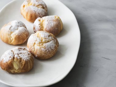 Beyaz tabakta pudra şekeri serpilir kek profiterol