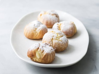 Beyaz tabakta pudra şekeri serpilir kek profiterol