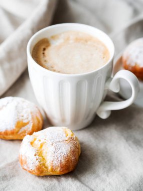 Kek profiterol bardak latte ile beyaz tabakta pudra şekeri serpilir