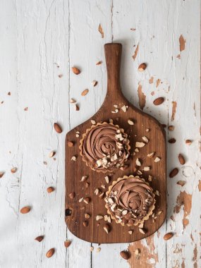 doğrama kurulu, üzerinde eski püskü Beyaz ahşap yüzey üzerinde badem fındık ile Çikolatalı tart hizmet