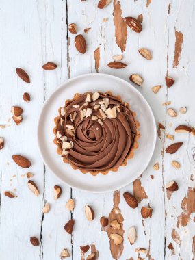 Beyaz tahta yüzeyi beyaz tabakta servis badem Fındıklı çikolata tart Üstten Görünüm