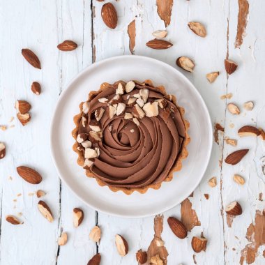 Beyaz tahta yüzeyi beyaz tabakta servis badem Fındıklı çikolata tart Üstten Görünüm