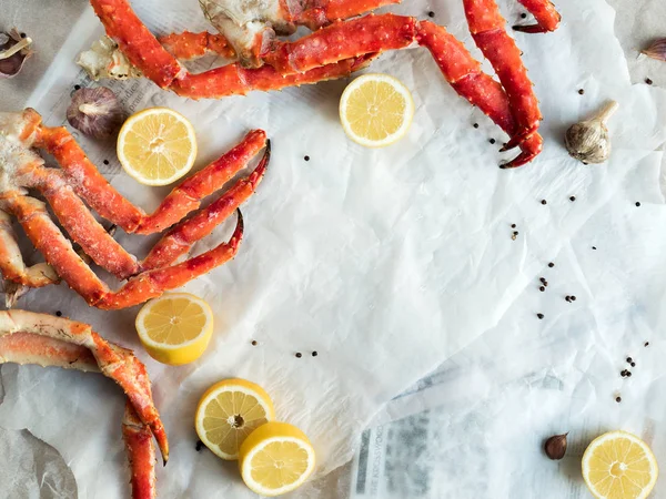 Top view of fresh crab legs with lemons and spices on crumpled paper