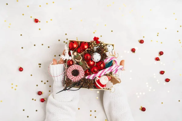 コピースペースと白い背景の上にヴィンテージクリスマス小道具木のおもちゃと箱を保持白いニットセーターの女性の手 クリスマスと新年の創造的なレイアウト — ストック写真