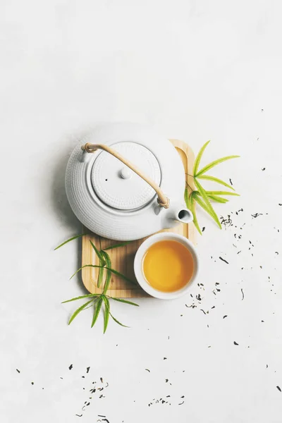コピースペースのある白い背景に乾燥した緑茶で囲まれた竹のマットにティーセットとアジアのお茶のコンセプト お茶の淹れ方 — ストック写真