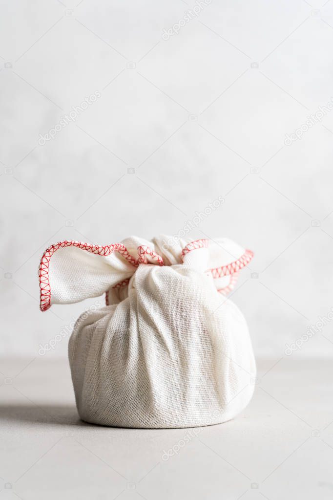 Furoshiki - Asian technique of wrapping tying items for gift, easy carrying. The white linen bag is knotted.