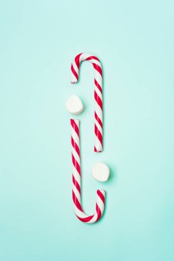 Noel ya da yeni yıl tatili için şeker kamışları ve marşmelovlarla donatılmış bir turkuaz arka plan ve fotokopi alanı. Noel aksesuarlı tebrik kartı.