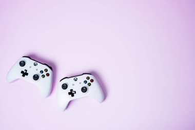 Moskova, Rusya - Juney 03 2019: Pembe pastel arka planda beyaz kablosuz oyun koruyucuları Xbox One S kumandası. Yaratıcı Asgari Oyun konsepti.