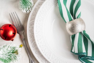 Beyaz tabaklar, çatal bıçak takımı, peçete ve Noel süsüyle Noel sofrası, keten masa örtüsünün üzerinde fotokopi alanı olan ağaç oyuncakları. Kış, yeni yıla özel konsept masa servisi.