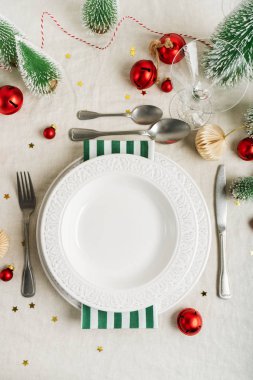 Beyaz tabaklar, cam, çatal bıçak takımı, şampanya ve Noel süslemeleri ile gri arka planda güzel bir masa. Kopyalama alanı olan tatil düzeni.
