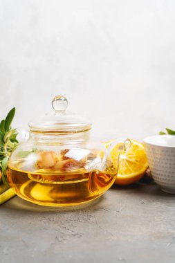 Taze zencefil, limon otu, adaçayı, adaçayı, bal ve limon karışımı koyu arkaplanda fotokopi alanı ile sağlıklı antioksidan ve antiinflamatuar zencefil çayı yapmak. 