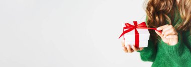 Yünlü yeşil kazaklı bir kadın hediye paketi ve bir fiyonk tutuyor. Noel şenliği düzeni. Yeni yıl için maket. Geniş pankart.