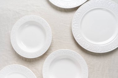 Keten masa örtüsündeki boş seramik tabakaların fotokopi alanı ile üst görünümü. Masa düzenine hazırlık. Yemek masası servisini kabul et. 