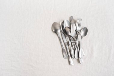 Keten masa örtüsü üzerinde gümüş çatal bıçak takımı. Tablo ayarına hazırlık