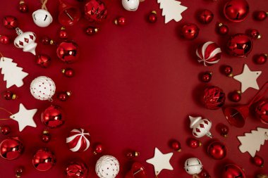 Kırmızı Noel ağacı süslemesi kırmızı arka planda yuvarlak bir çerçeve şeklinde ve fotokopi alanı içeriyor. Yeni yıl tebrik kartı planı. Asgari düzeyde. Düz yatıyordu.