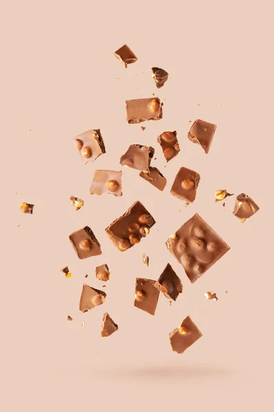 Pile of the chunks of broken different chocolate bars with nuts isolated on white with space for text. Background with chocolate. Sweet food photo concept.